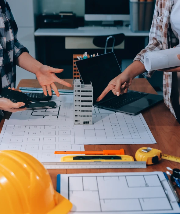 Construction team reviewing blueprints and scale model.